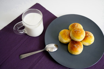 Breakfast bread and a glass of milk on a white table with a purple mat