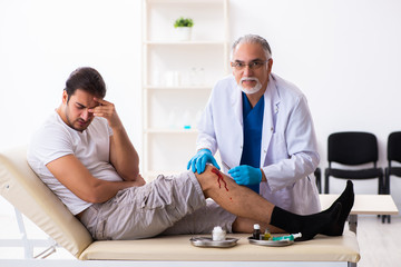 Leg injured man visiting old doctor in first aid concept
