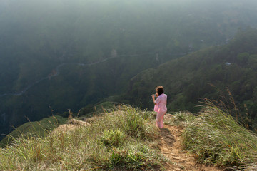 Girl enjoys a mountain view while standing on a cliff