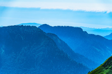 Green mountain slope. Layers of mountains in the haze during sunset. Krasnaya Polyana, Sochi,...