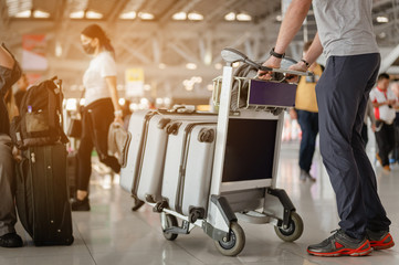 Travelers are walking to drag luggage in modern airport terminal to travel to new places. Rear view. Copy space. Luggage, traveler, travel, airport, walking, holiday concept.