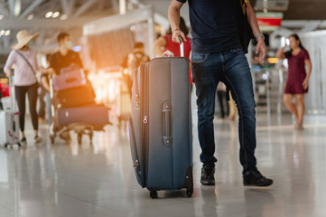Travelers are walking to drag luggage in modern airport terminal to travel to new places. Rear...