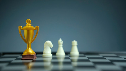 Business strategy conceptual photo – Golden trophy standing on chessboard with chess pawn