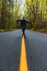 girl walking down highway through trees