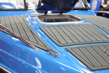 Gray marine teak on blue motor boat bow deck close up with opened porthole window