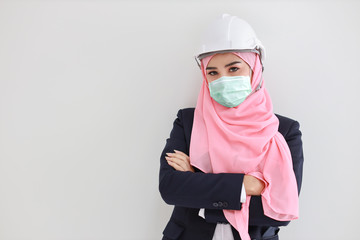 Beautiful engineer muslim young asian woman wearing blue suit with medical protective face mask to protect infection from Coronavirus in studio on isolated white background portrait. Covid-19 concept