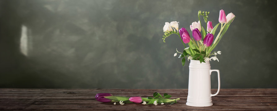 spring flowers in white jug on dark background