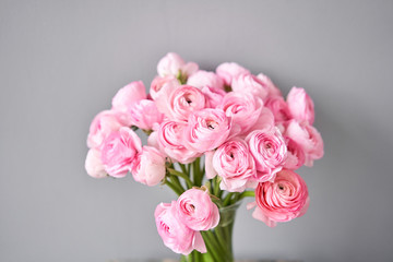 Spring background, flower Wallpaper. Persian buttercup. Bunch pink ranunculus flowers on light gray background. Vase on vintage wooden table. Wallpaper