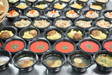 Row of plastic disposable lunch box with healthy natural food. Soups, cream soup, main course with side dish, salads. Food delivery. Lunch in the office.