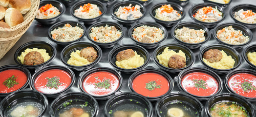 Row of plastic disposable lunch box with healthy natural food. Soups, cream soup, main course with side dish, salads. Food delivery. Lunch in the office.