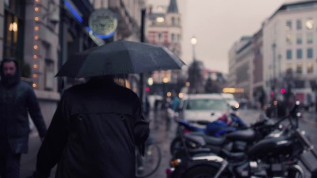 A person walking with a black umbrella.