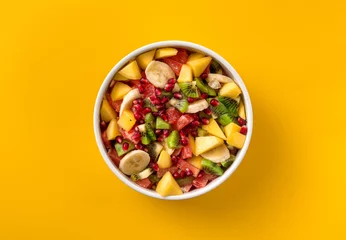 Photo sur Plexiglas Manger Mixed fruit salad in plate on yellow background top view Diet summer food concept
