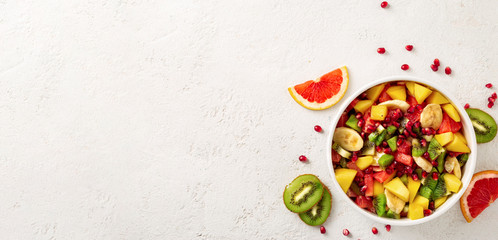 Fruit salad bowl on light surface with copy space top view Diet food concept