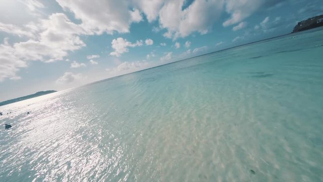 Aerial footage flying over the sunny beach close to the water FPV