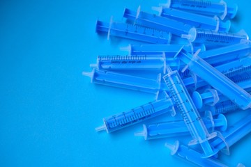 Medicine and health concept. Blue plastic syringes close-up on a bright blue background....