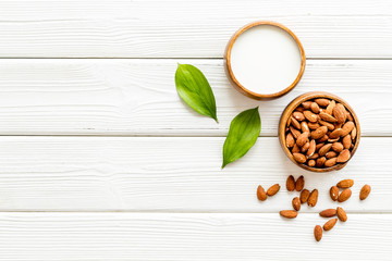Almond milk near nuts on white wooden background top-down copy space