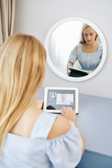 Young woman sitting at her vanity and having telemedicine session with her physician