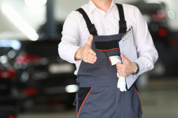 Close-up of car mechanic in uniform offer to shake hands in garage. Service station and fix vehicle concept. Professional automobile maintenance and repair