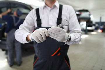 Fototapeta premium Close-up view of male specialist showing mechanical tool for fixing automobiles. Service station and car maintenance concept. Special professional equipment for garage worker