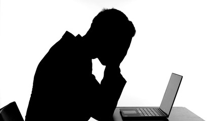The Silhouette of Upset Man Working on his Laptop