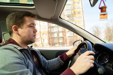 man in grey sweater behind wheel of car 