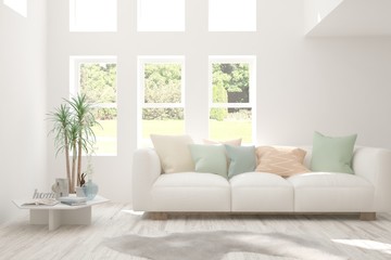 Minimalist living room in white color with sofa and summer landscape in window. Scandinavian interior design. 3D illustration