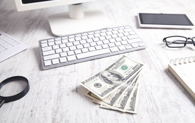 Hundred dollar banknotes with a computer keyboard, tablet and calculator.