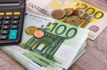 Euro banknotes with calculator and coins on a wooden background. Close-up. Business concept.