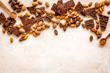 Chocolate frame. Broken slices and nuts on light background top-down copy space