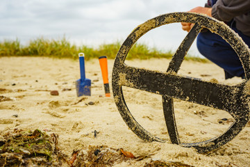 Man with metal detector on sea beach