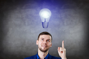 Businessman thinking and pointing finger on light bulb over head.