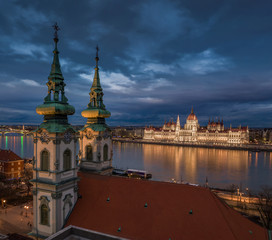 Fototapeta premium Budapeszt, Węgry - widok z lotu ptaka kościoła parafialnego św.Anny na placu Batthyany o zmierzchu z oświetlonym budynkiem parlamentu węgierskiego w tle
