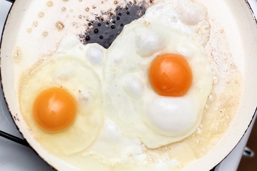 Frying eggs. Making sunny side up eggs with black pepper and salt.