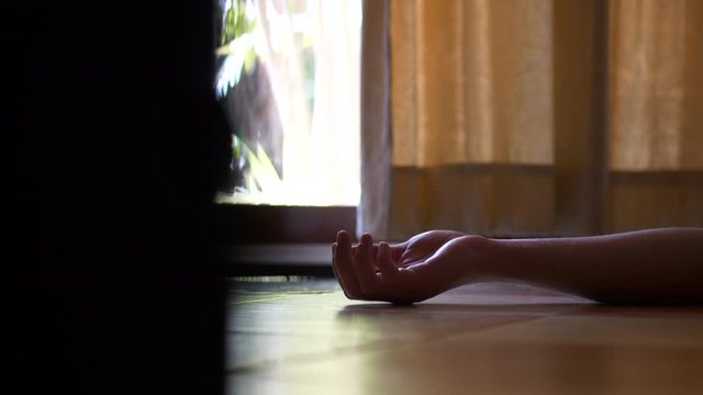 Disquieting scene of hand of person lying on floor.