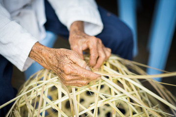 Old woman hands weaving chicken coop.Traditional Thai chicken coop.