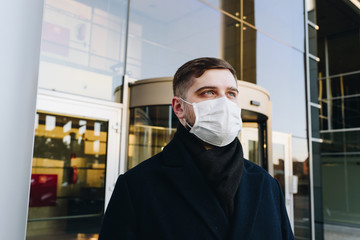 Fototapeta na wymiar Caucasian young man near his office wearing surgical face mask to protect from coronavirus covid-19 covid 19 virus