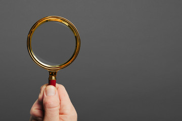 man holds a magnifier on a black background