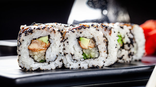 Japanese cuisine. Rolls with sea eel, avocado, cucumber and black caviar. Close-up. Serving dishes in a restaurant on a dark plate. background image, copy space text