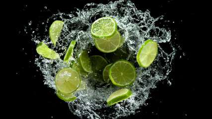 Fototapeta na wymiar Flying lime slices in water splash