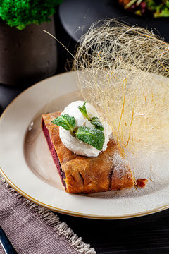 German Turkish cuisine. Strudel pie with cherry, a ball of ice cream on top and caramel cobweb decor. Serving dishes in a restaurant in a white plate. background image, copy space
