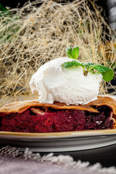 German Turkish cuisine. Strudel pie with cherry, a ball of ice cream on top and caramel cobweb decor. Serving dishes in a restaurant in a white plate. background image, copy space