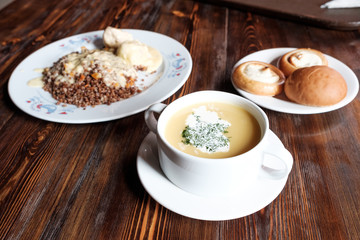 lunch on a wooden table. dishes with buckwheat and soup with muffins