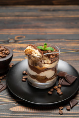 Classic tiramisu dessert in a glass cup on wooden background
