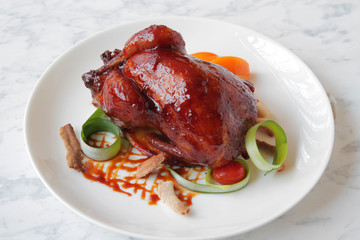  Baked, tasty juicy, quail with spices herbs and soy sauce, beautifully served on a marble table