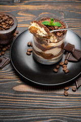 Classic tiramisu dessert in a glass cup on wooden background