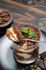 Classic tiramisu dessert in a glass cup on wooden background