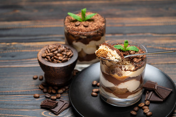 Classic tiramisu dessert in a glass cup on wooden background
