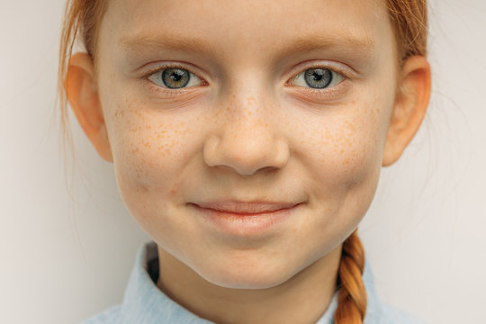 Close-up Portrait Of Beautiful Smiling Child Girl With Red Hair, Adorable Girl With Freckles And Unusual Natural Beauty Look At Camera And Smile, She Is In Good Mood. Isolated White Background