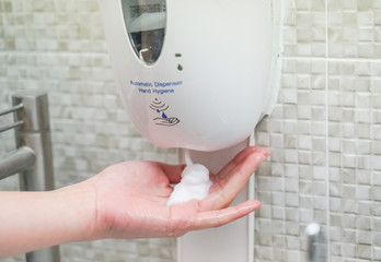 close up woman hand using automatic dispenser hand sanitizer for hands hygiene at home or public space, hospital clinic for protect covid 19 spread epidemic prevention.