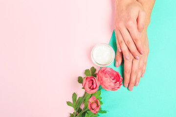 female  manicure. Beautiful young woman's hands with cream  on pastel background .